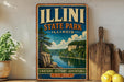 A vintage-style sign for Illini State Park in Illinois, featuring a scenic illustration of a river and forest landscape.