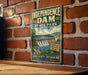 A vintage-style sign for Independence Dam, a landmark in Ohio, is displayed on a brick wall.