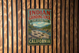 A vintage metal sign for Indian Grinding Rock State Historic Park in California, featuring a scenic landscape with mountains and a river.