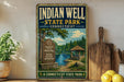 A vintage-style sign for Indian Well State Park in Connecticut, featuring a scenic illustration of a lake, trees, and a gazebo.