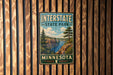 A vintage metal sign for Interstate State Park in Minnesota, featuring a scenic landscape with a river, mountains, and pine trees.