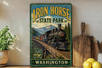 a vintage-style sign for Iron Horse State Park in Washington, with a train depicted on the sign. The sign is displayed on a wall, surrounded by various kitchen items such as a cutting board, a knife, and a bowl.