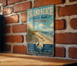 A vintage-style metal sign for Island Beach State Park in New Jersey, featuring a beach scene with a lighthouse and birds in the sky.