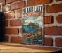 A vintage-style metal sign for the Island Lake Recreation Area in Michigan, featuring a scenic image of a lake, canoe, and surrounding forest.