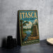 A vintage-style metal sign for itasca State Park in Minnesota, featuring a scenic landscape with a river, pine trees, and a monument.