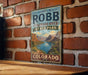 A vintage-style metal sign for James M. Robb Colorado River State Park is displayed on a brick wall.