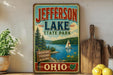 A vintage-style sign for Jefferson Lake State Park, featuring a scenic illustration of a lake, pine trees, and a sailboat.