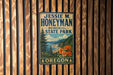 A metal sign with the name "JESSIE M. HONEYMAN MEMORIAL STATE PARK" and the word "OREGON" is displayed on a wooden wall.