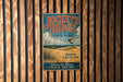 A vintage metal sign for Jockey's Ridge State Park, featuring a beach scene and a bird in flight, mounted on a wooden wall.