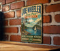A vintage-style metal sign for Joe Wheeler State Park in Alabama, featuring a scenic illustration of a lake and a sailboat.