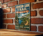 A vintage-style metal sign for the Johnson-Sauk Trail, advertising the State Recreation Area, is displayed on a brick wall.