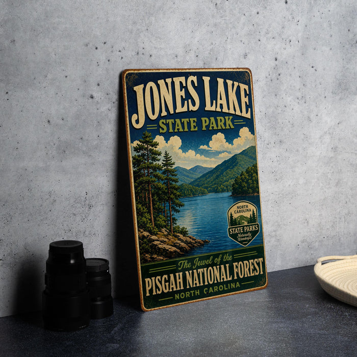 A vintage-style sign for Jones Lake State Park, featuring a scenic landscape with pine trees, a lake, and mountains in the background.