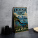A vintage-style sign for Kachemak Bay State Park in Alaska, featuring a scenic landscape with mountains, a lake, and a bald eagle in flight.