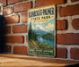A vintage metal sign for Kanaskat-Palmer State Park in Washington, featuring a scenic mountain landscape with a lake and forest.