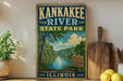 A vintage-style sign for Kankakee River State Park in Illinois, featuring a scenic illustration of the river surrounded by lush greenery.