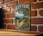 A vintage-style metal sign for Katy Trail, Missouri, mounted on a brick wall.