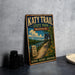 A vintage-style metal sign for Katy Trail State Park, Missouri, featuring a scenic illustration of a trail, bridge, and surrounding nature.