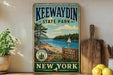A vintage-style metal sign for Kewaydin State Park, featuring a scenic landscape with a lake, pine trees, and a sailboat.