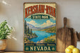 A vintage-style sign for Kershaw-Ryan State Park in Nevada, featuring a scenic landscape with mountains, a lake, and pine trees.