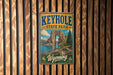 A vintage-style metal sign for Keyhole State Park in Wyoming, featuring a scenic landscape with a large rock formation and a lake.