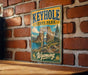 A vintage-style metal sign for Keyhole State Park in Wyoming, featuring a scenic landscape with a large rock formation and a lake.