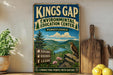 A vintage-style sign for the Kings Gap Environmental Education Center in Pennsylvania, featuring a scenic mountain landscape with a bird perched on a rock.