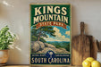 A vintage-style sign for Kings Mountain State Park in South Carolina, featuring a scenic landscape with a tree and rocky outcroppings.