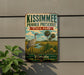A vintage-style metal sign for Kissimmee Prairie Preserve, featuring a bird and palm trees, is mounted on a wall next to a plant.