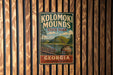 A vintage metal sign for Kolomaki Mounds State Park in Georgia, featuring a scenic landscape with a hill, river, and a pottery piece.