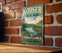 A vintage metal sign for Kooser State Park in Pennsylvania, featuring a scenic landscape with a lake and mountains.