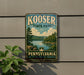 A vintage metal sign for Kooser State Park in Pennsylvania, featuring a scenic landscape with a lake and mountains.