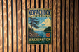 A vintage metal sign for Kopachuck State Park in Washington, featuring a scenic landscape with a lake and pine trees.