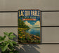 A vintage-style metal sign for Lacqui Parle State Park in Minnesota, featuring a scenic landscape with a lake, trees, and flowers.