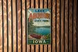 A vintage metal sign for Lake Ahwatukee State Park in Iowa, featuring a scenic image of a lake with a canoe and a sailboat.