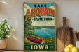 A vintage-style poster advertising Lake Ahwatukee State Park in Iowa, featuring a scenic image of a lake with a red canoe and a sailboat.