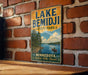 A vintage-style metal sign for Lake Bemidji State Park in Minnesota, featuring a scenic illustration of a lake surrounded by pine trees and a canoe.