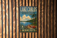 A vintage metal sign for Lake Carlos State Park in Minnesota, featuring a scenic illustration of a lake, canoe, and surrounding landscape.