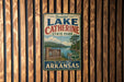 A vintage-style metal sign for Lake Catherine State Park in Arkansas, featuring a scenic landscape with a lake, mountains, and a sign indicating the park as the "Natural State of Arkansas".