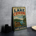 A vintage-style sign for Lake Catherine State Park in Arkansas, featuring a scenic image of the lake and surrounding landscape.