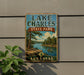 A vintage metal sign for Lake Charles State Park in Arkansas, featuring a scenic landscape with a river, pine trees, and a boat on the water.