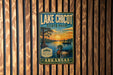 A vintage-style sign for Lake Chicot State Park in Arkansas, featuring a duck and a sunset over a lake.