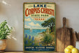 A vintage-style sign for Lake Corpus Christi State Park in Texas, featuring a sailboat on the water and a desert landscape with blue flowers.