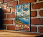 A vintage-style metal sign for Lake Elmo State Park in Montana, featuring a scenic landscape with mountains, trees, and a lake.