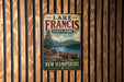 A vintage metal sign for Lake Francis State Park in New Hampshire, featuring a scenic image of a lake with a canoe and mountains in the background.