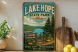 A vintage-style sign for Lake Hope State Park in Ohio, featuring a scenic landscape with a lake, mountains, and pine trees.