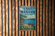 A vintage-style metal sign for Lake Manawa State Park in Iowa, featuring a scenic image of a lake, canoe, and surrounding landscape.