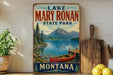 A vintage-style sign for Lake Mary Ronan State Park in Montana, featuring a scenic image of a lake, mountains, and a red canoe.