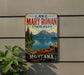 A vintage-style metal sign for Lake Mary Ronan State Park in Montana, featuring a scenic image of a lake, mountains, and a red canoe.