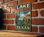 A vintage-style sign for Lake Mineral Wells State Park in Texas, featuring a scenic landscape with a lake and mountains.