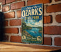 A vintage-style sign for Lake of the Ozarks State Park in Missouri, featuring a scenic illustration of the lake and surrounding landscape.